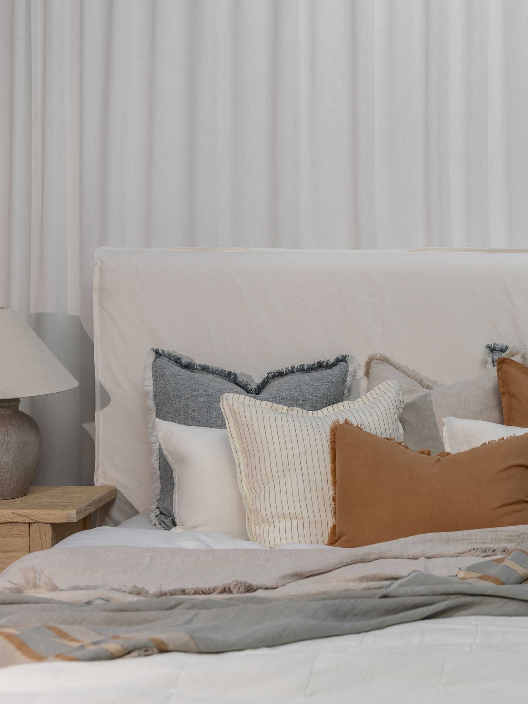 Arlo seagrass woven French Flax linen striped throw draped over bed with herringbone texture and fringed edges