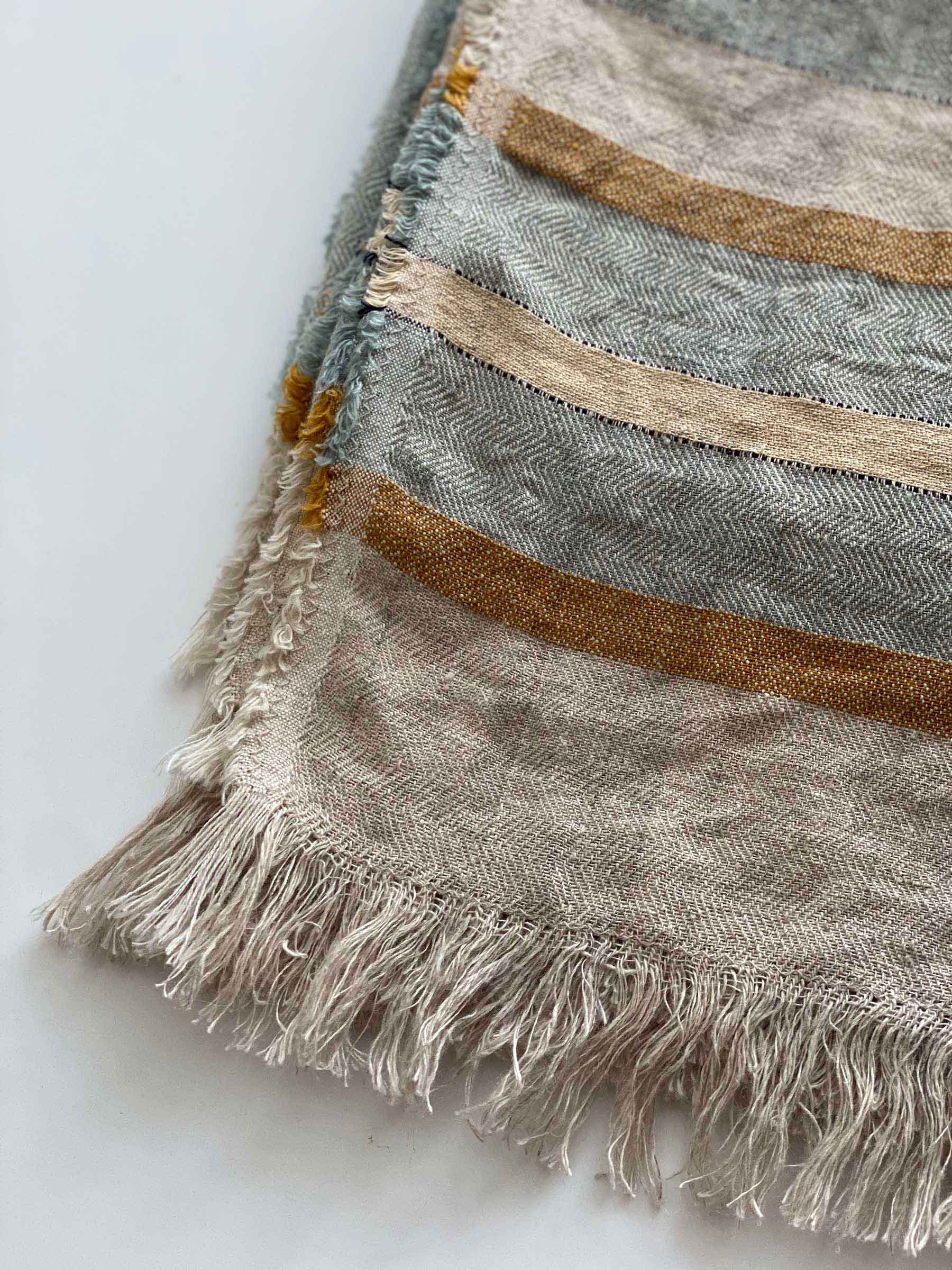 Close-up of Arlo seagrass woven linen throw showing yarn-dyed stripe detail and fringed edge texture