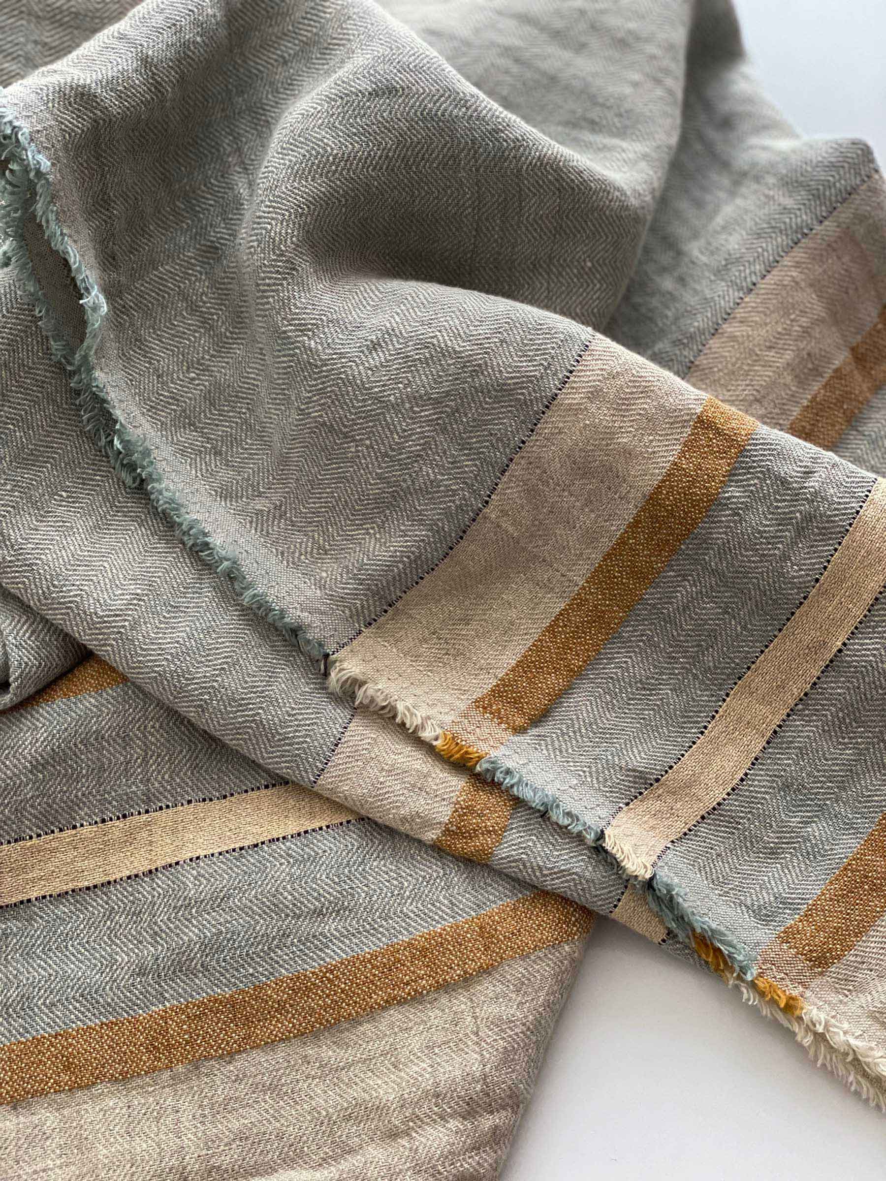 Close-up details of Arlo woven striped throw with fringed edges and herringbone weave made from 100% French linen in seagrass colour