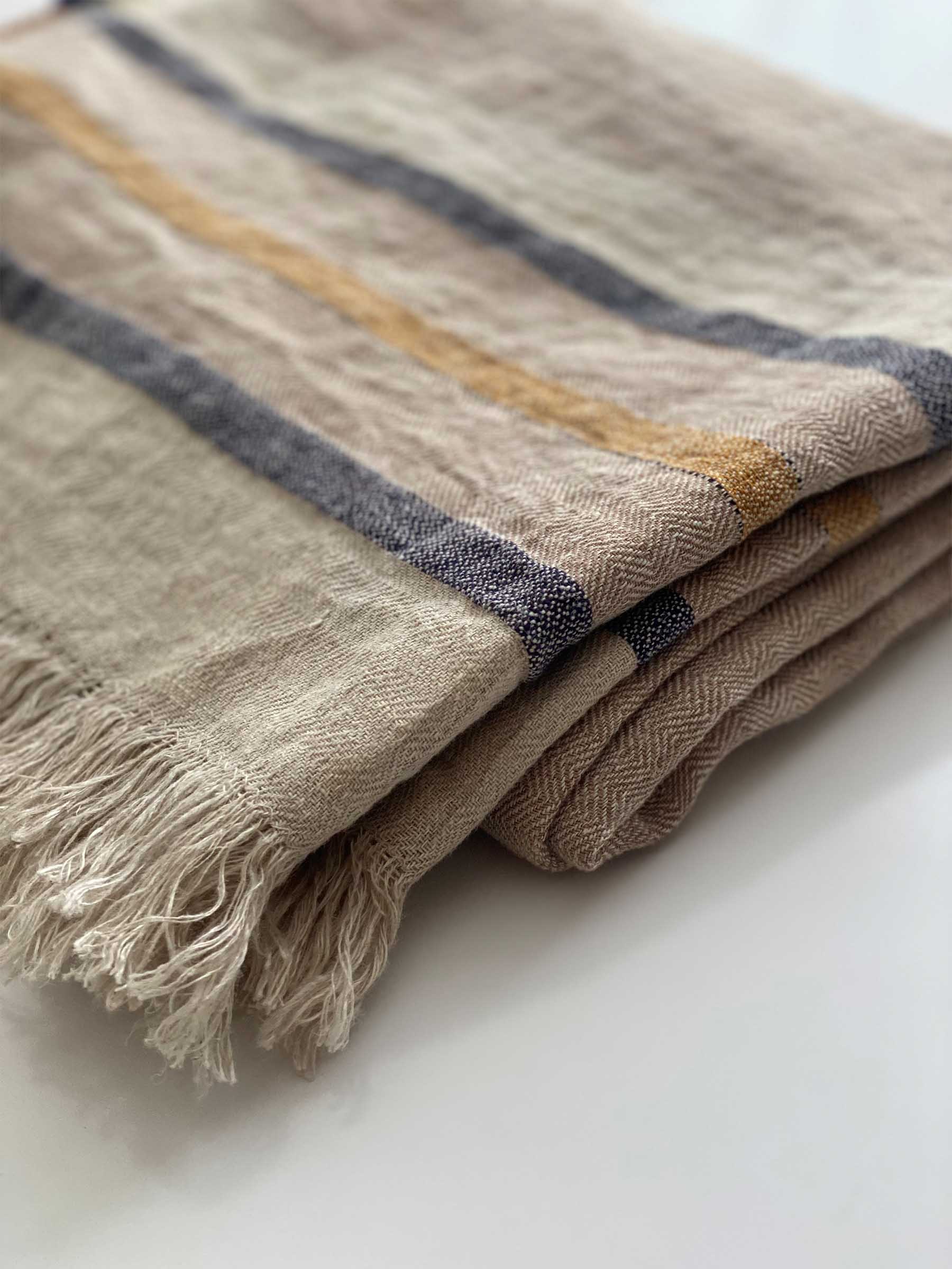 Close up detail of Arlo woven french flax linen throw in sand dune colour showing its fringed edges and herringbone weave