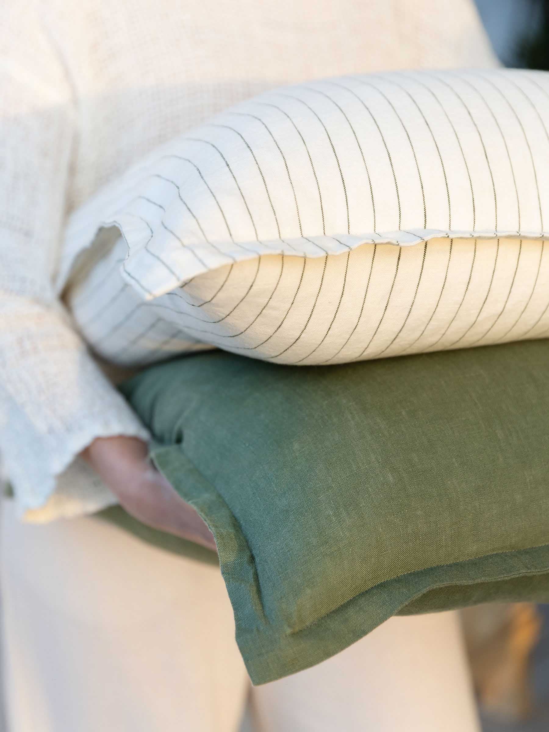 Felix Basil green french flax linen cushion stacked to show its pairing with an olive striped cushion