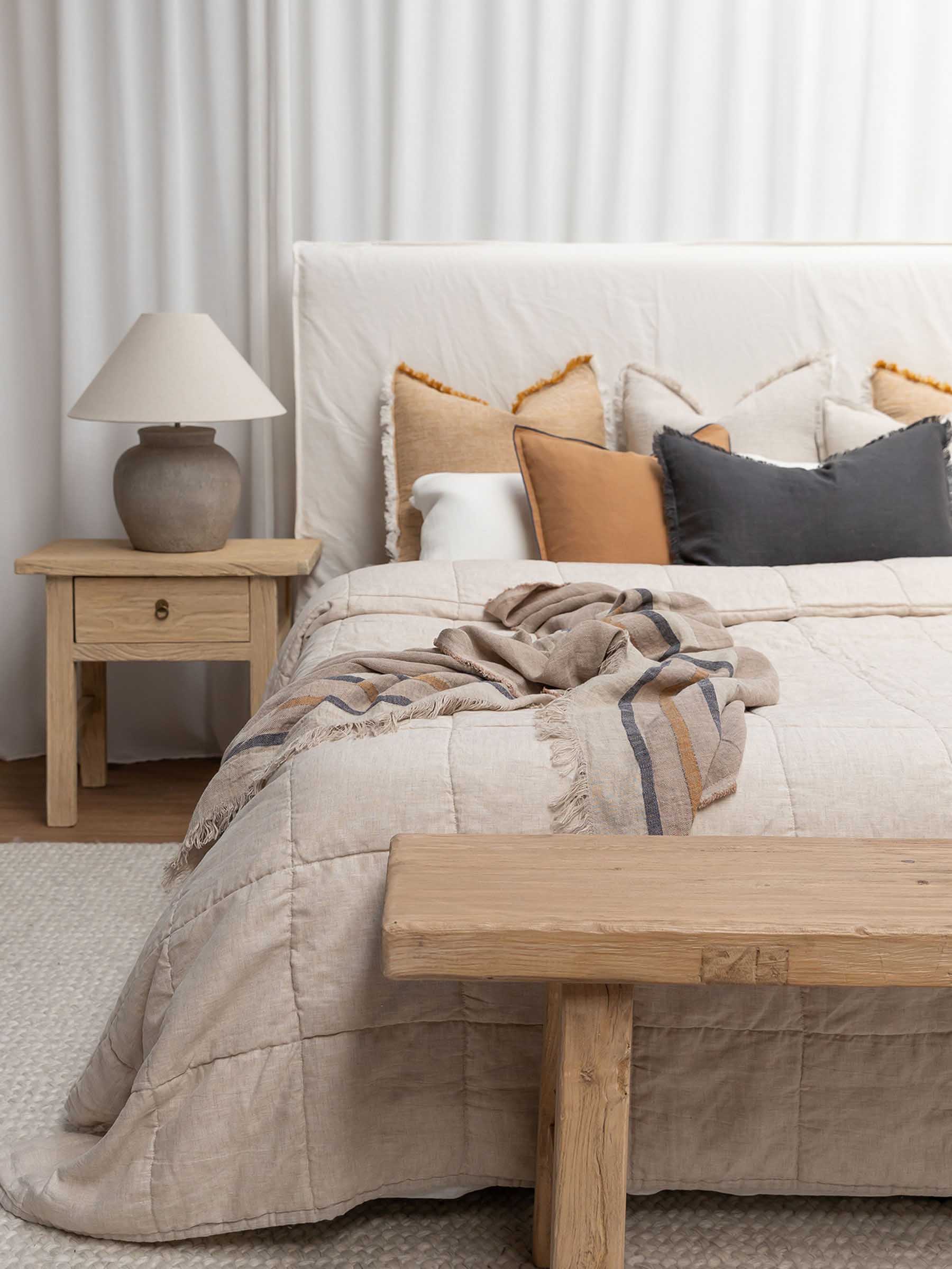 Harlow French Flax linen cushion in Butterscotch colour 50cm square with graphite overstitching trim displayed on bed in contemporary bedroom