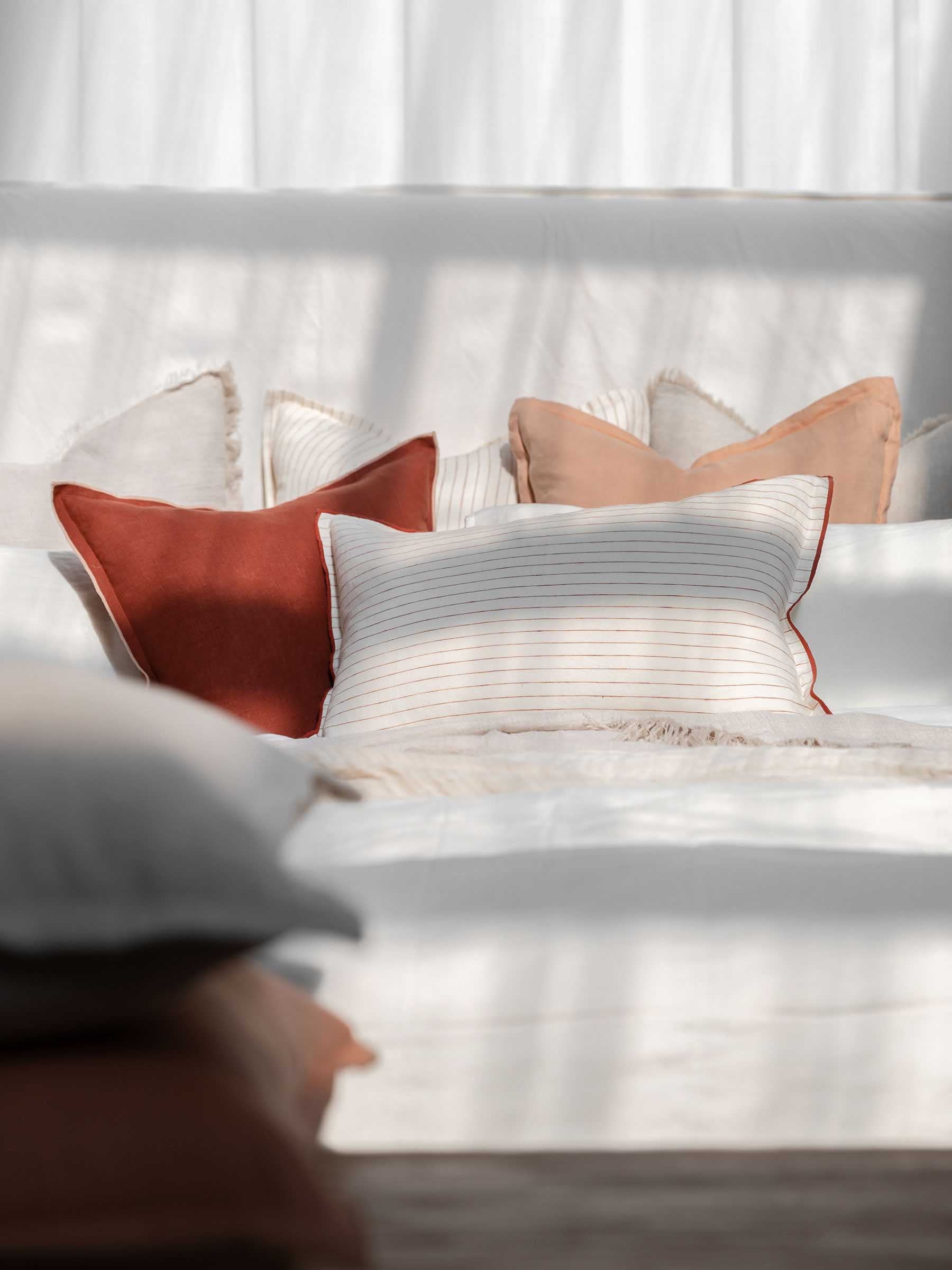 Harlow French Flax linen cushion in Merlot colour 50cm square with soft pink overstitching trim styled on neutral contemporary bed