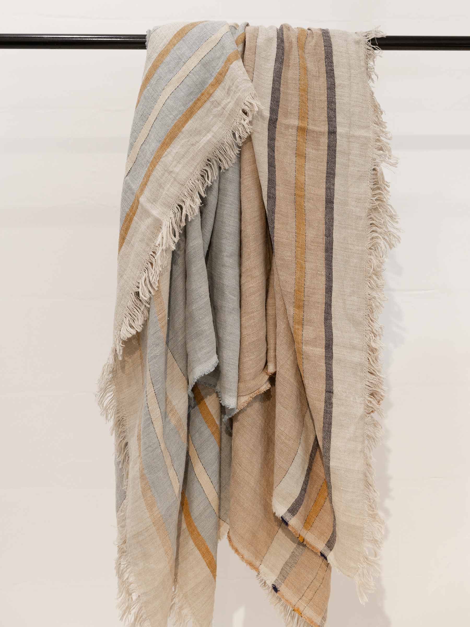 Arlo woven stripe French Flax linen throw collection in all available colours sand dune and seagrass hanging to show fringed edges and texture