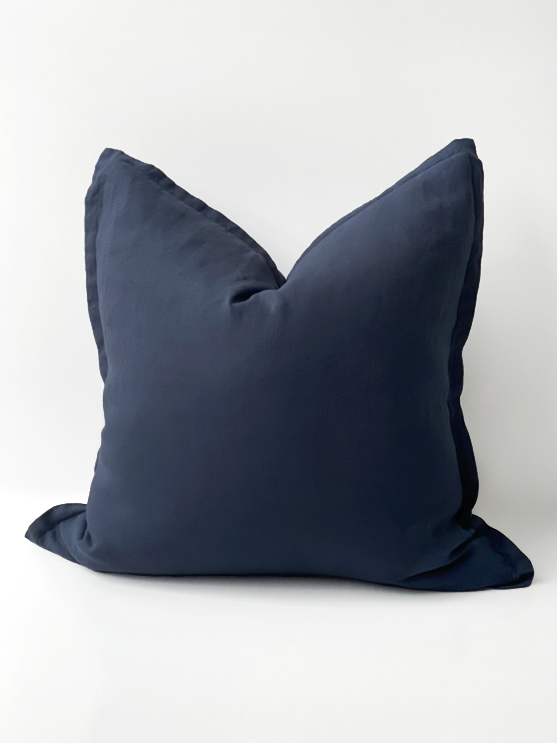 Reversi® reversible linen flange square cushion flipped to show full navy colour of the two in one cushion cover design in a studio