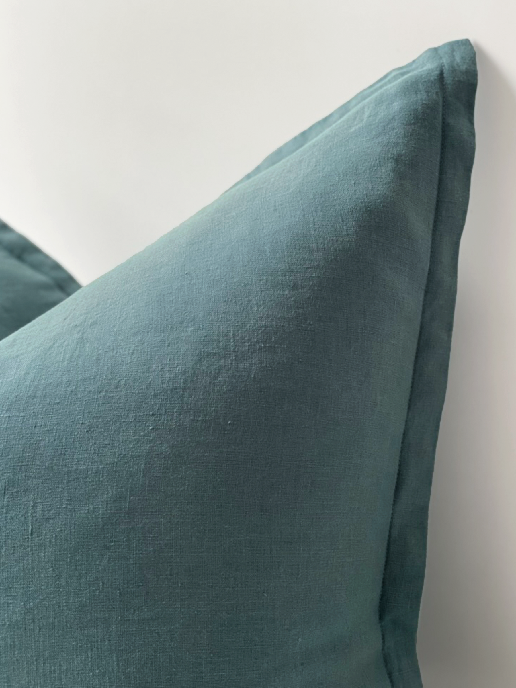 Reversi® reversible linen flange square cushion flipped to show petrol colour texture close up of the two in one cushion cover design in a studio